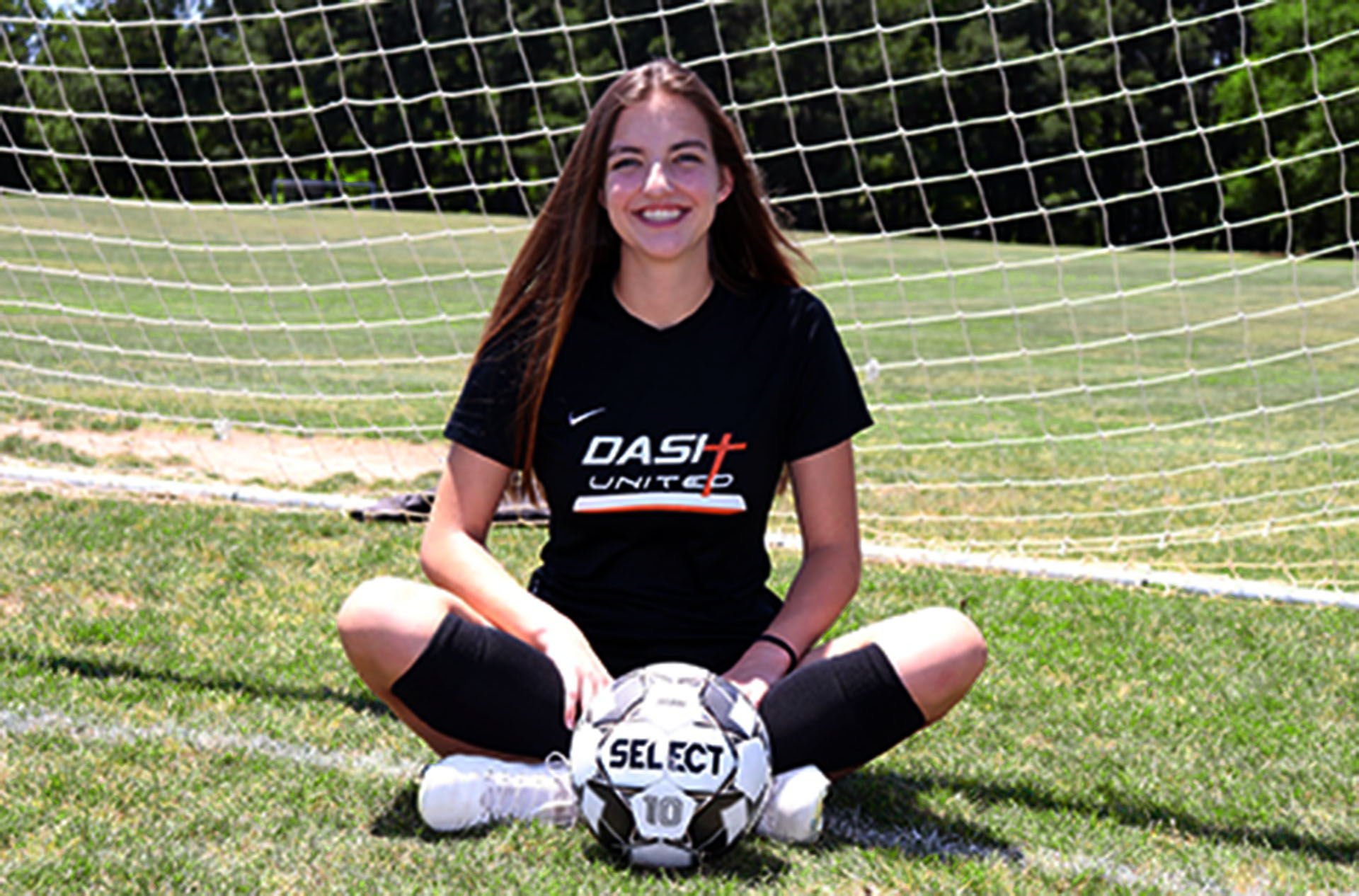 girl sitting behind soccer ball